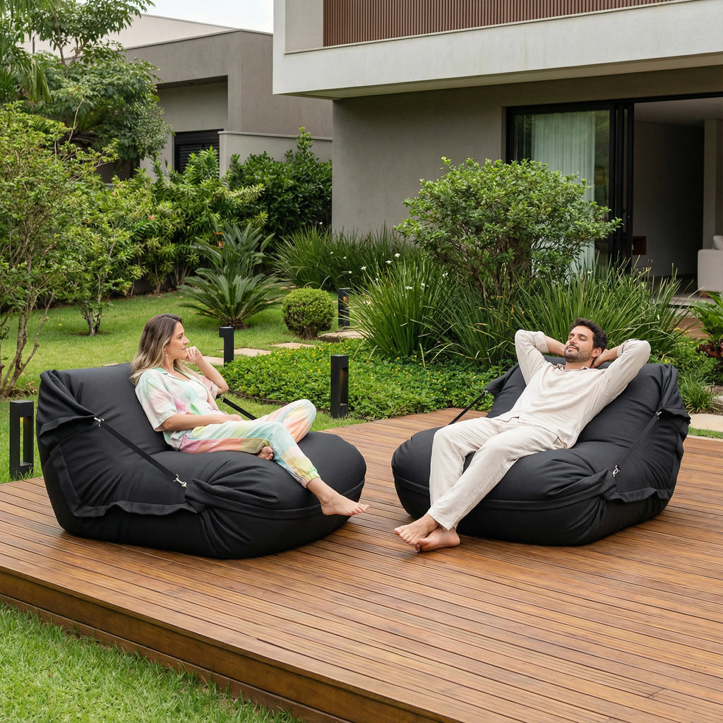 Casal relaxando em puffs pretos Geribá sobre um deck de madeira